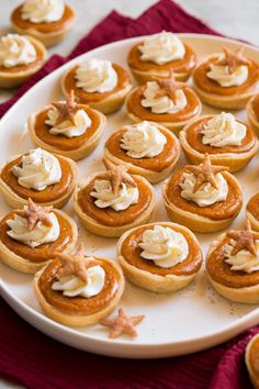 a white plate topped with mini pumpkin pies covered in whipped cream and starfish