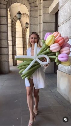 a woman is walking down the street with flowers in her hand and she is holding a bunch of tulips