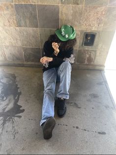 a person sitting on the ground wearing a green hat