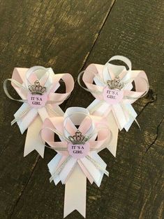 three pink ribbon bows with tiaras on them sitting on a wooden surface, the ribbons have been cut in half