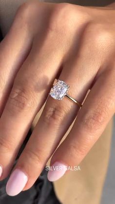 a woman's hand with a ring on her finger and an oval shaped diamond in the middle