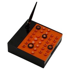 an orange and black electronic device with buttons on it's back side, in front of a white background