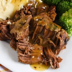 some meat and broccoli on a plate with gravy, mashed potatoes