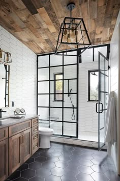 a bathroom with black and white tile flooring and wood accents on the walls, along with a wooden ceiling