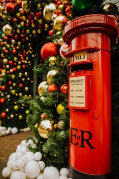 a red mail box sitting next to a christmas tree