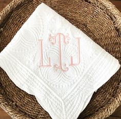 the monogrammed dish towel is on top of a woven basket with a pink monogrammed napkin