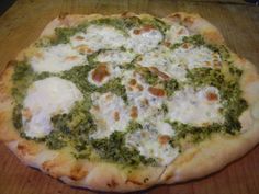 a pizza sitting on top of a wooden cutting board covered in cheese and spinach