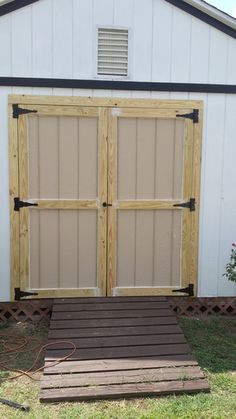 two wooden doors are open in front of a shed