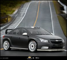 a black car driving down a road next to a forest