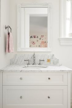 a white bathroom with marble counter top and sink under a large mirror above the vanity