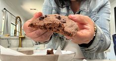 a woman holding a chocolate cookie in her hands