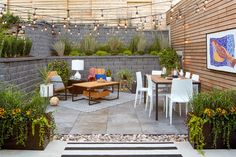 an outdoor patio with white chairs and wooden tables surrounded by greenery on the wall