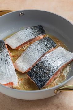 three fish are cooking in a frying pan