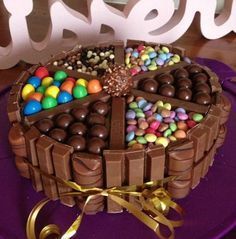 there is a chocolate cake decorated with candy and candies on the purple platter