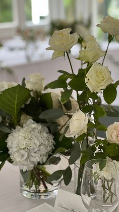 two vases filled with white flowers sitting on top of a table next to each other