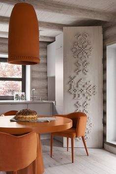 an orange table and chairs in a room with wood walls, white flooring and large windows