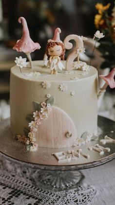 there is a cake decorated with figurines and flowers on the top of it