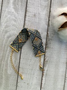 a blue and gold bracelet sitting on top of a wooden table next to a cotton ball