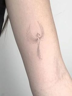 a woman's arm with a small bird tattoo on the back of her left arm