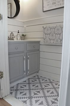 a bathroom with gray cabinets and white walls