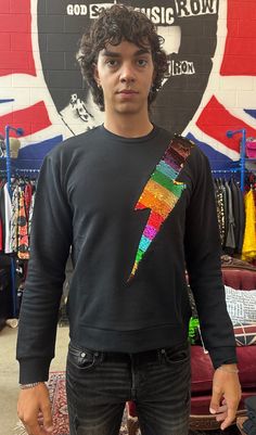 a young man standing in front of a wall with a rainbow colored kite on it