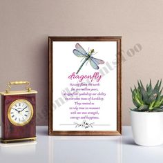 a framed print with a dragonfly on it next to a clock and potted plant