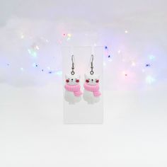 two white cats wearing pink scarfs and earrings