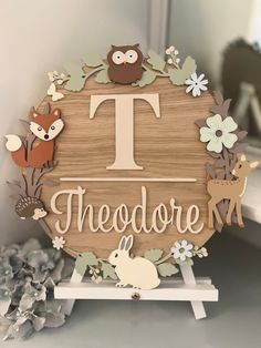 a wooden sign that says theodore with animals and flowers on the front, sitting on a shelf