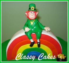 there is a cake that looks like a lepreite sitting on top of a rainbow