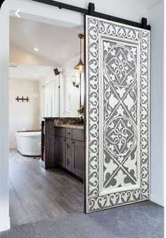 an open door leading to a bathroom with wood flooring and white tile on the walls