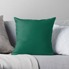 a green pillow sitting on top of a couch next to two white pillows and a blanket