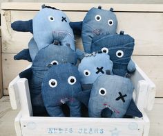 a group of stuffed animals sitting inside of a wooden crate with eyes drawn on them