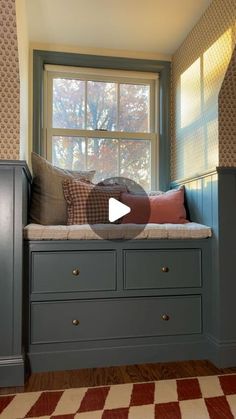 a window seat with pillows on it in front of a checkered floor and wallpaper