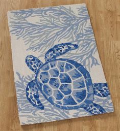 a blue and white turtle rug sitting on top of a wooden floor next to a wood floor