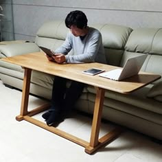 a man sitting at a table with a laptop and tablet in front of his face