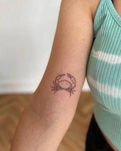 a woman's arm with a crab tattoo on the left side of her arm