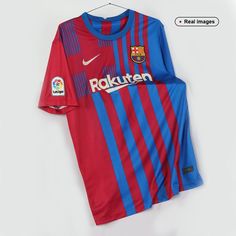 a red and blue soccer jersey hanging on a hanger next to a white wall