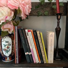 there is a vase with flowers and books on the shelf next to it, along with several other books