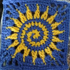 a crocheted square with yellow and blue details