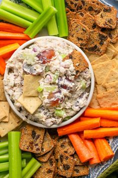 a platter filled with crackers, celery, carrots and dip