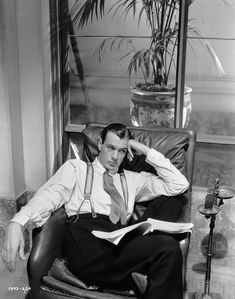 a man sitting in a chair with his hands on his head while reading a book