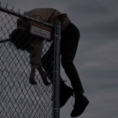 a man climbing up the side of a fence with his foot on top of it