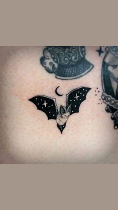 a woman's chest with tattoos on it and a bat flying through the air