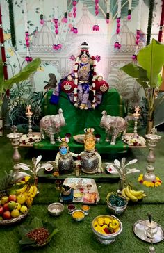 an idol sitting on top of a green couch next to bowls of fruit and vegetables