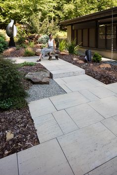 a woman sitting on a bench in the middle of a garden with rocks and gravel