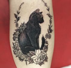 a black cat sitting on top of a white flowered branch with leaves and flowers around it