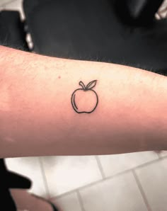 a small apple tattoo on the arm