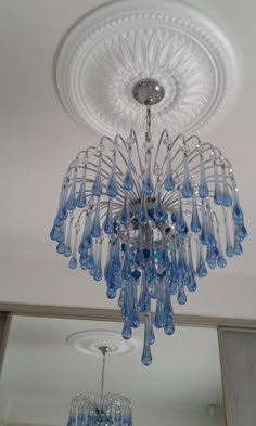 a blue chandelier hanging from the ceiling in a room with white walls and ceilings