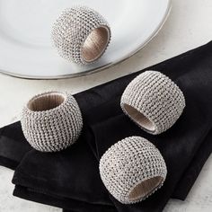 two napkin rings sitting on top of a black cloth next to a plate and fork