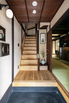 there is a wooden staircase leading to the second floor in this modern house with white walls and wood floors